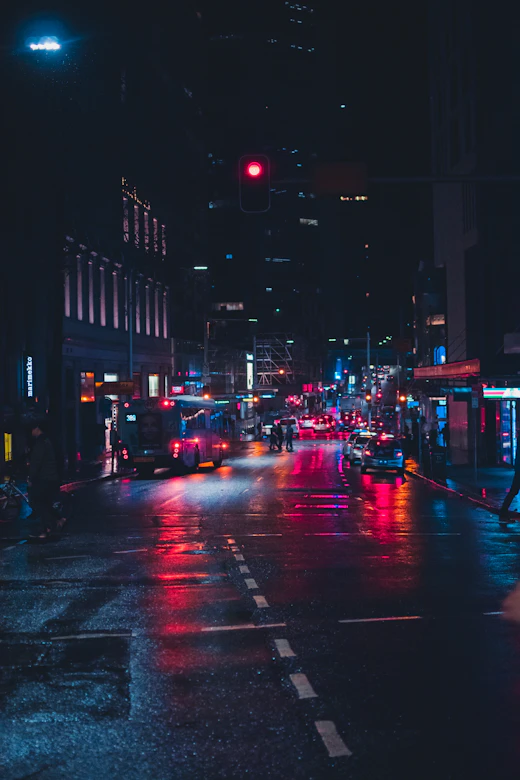 Neon-lit city street reflected on wet asphalt at night