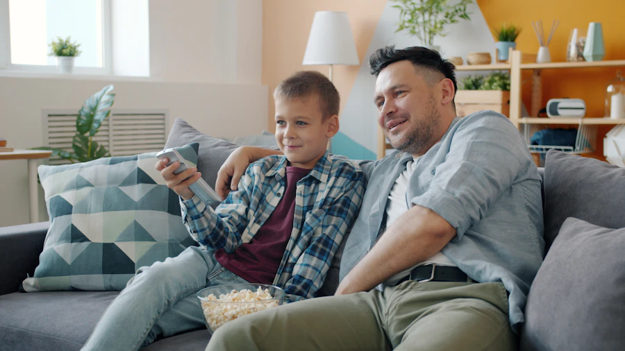 Dad and son sharing popcorn while watching cartoons on the couch
