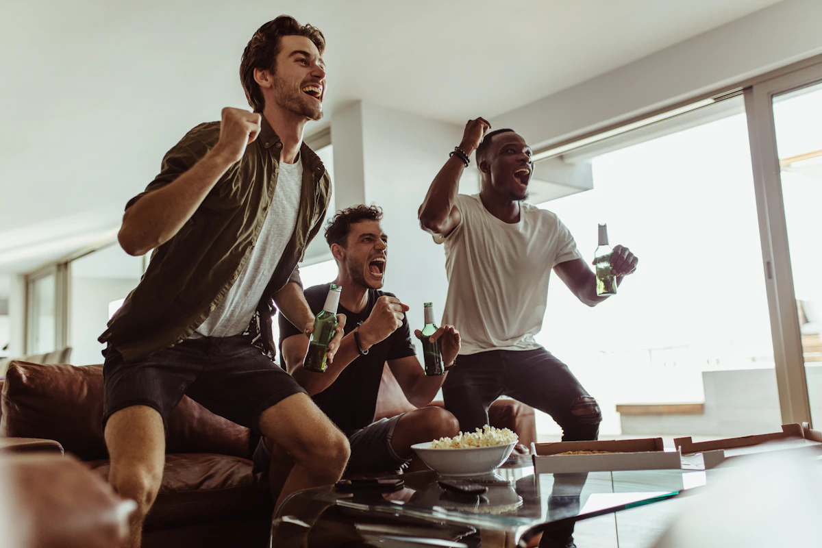 Friends celebrating on the couch while watching live sport together